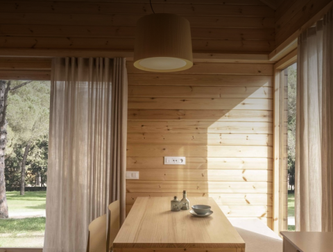 Interior de madera clara en la tiny house Bungalow «Duplex» de Wecamp Cala Montgó, España, con vistas a la naturaleza.