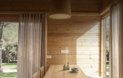 Interior de madera clara en la tiny house Bungalow «Duplex» de Wecamp Cala Montgó, España, con vistas a la naturaleza.