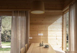 Interior de madera clara en la tiny house Bungalow «Duplex» de Wecamp Cala Montgó, España, con vistas a la naturaleza.