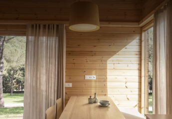 Interior de madera clara en la tiny house Bungalow «Duplex» de Wecamp Cala Montgó, España, con vistas a la naturaleza.
