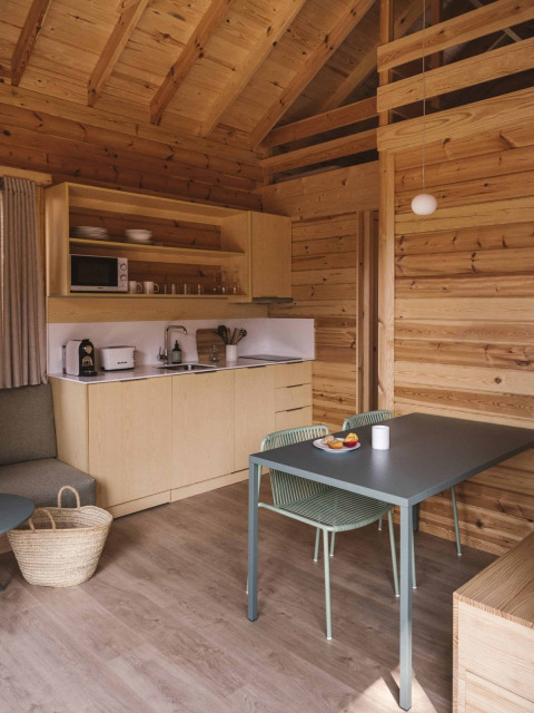 Acogedor interior de madera en la tiny house Bungalow «Duplex» de Wecamp Cala Montgó, con cocina y mesa.
