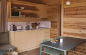 Acogedor interior de madera en la tiny house Bungalow «Duplex» de Wecamp Cala Montgó, con cocina y mesa.