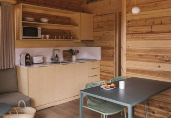 Acogedor interior de madera en la tiny house Bungalow «Duplex» de Wecamp Cala Montgó, con cocina y mesa.