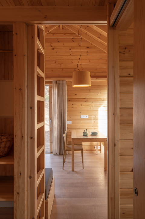Interior de la tiny house de madera Bungalow 'Duplex' en Wecamp Cala Montgó, España, con comedor visible.