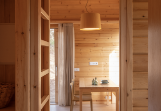 Interior de la tiny house de madera Bungalow 'Duplex' en Wecamp Cala Montgó, España, con comedor visible.