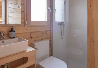 Baño moderno de madera con ducha, inodoro y lavabo en una pequeña casa en Wecamp Cala Montgó, España.