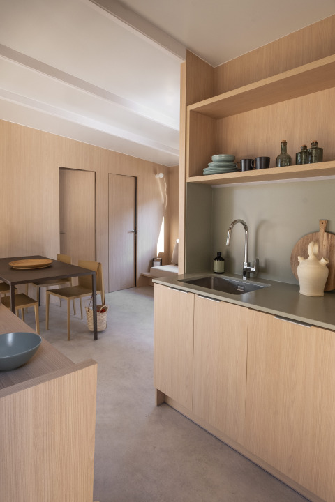 Moderne glamping-keuken en eetgedeelte met lichte houtafwerkingen en minimalistisch Scandinavisch design.