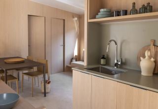 Moderne glamping-keuken en eetgedeelte met lichte houtafwerkingen en minimalistisch Scandinavisch design.