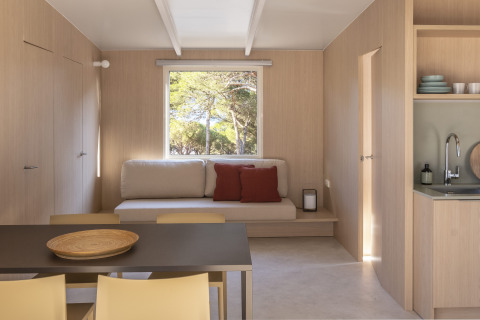 Modern tiny house interieur met houten wanden, eettafel en bank bij Wecamp Cala Montgó, Spanje.