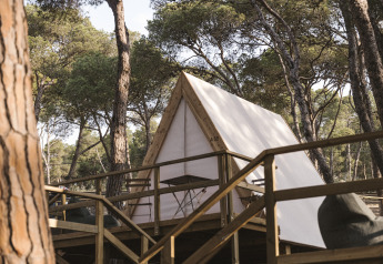 Tente safari Cabin Tent au Wecamp Cala Montgó en Espagne, sur une terrasse en bois au milieu des pins.