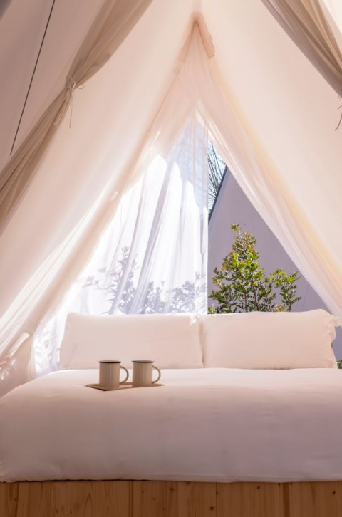 Vista interna di una tenda safari luminosa con letto accogliente e due tazze a Wecamp Cala Montgó, Spagna.
