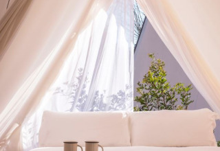 Vista interna di una tenda safari luminosa con letto accogliente e due tazze a Wecamp Cala Montgó, Spagna.