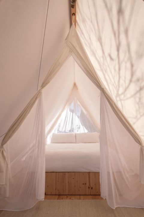 Vista interna di una tenda safari Cabin con letto bianco al Wecamp Cala Montgó in Spagna.