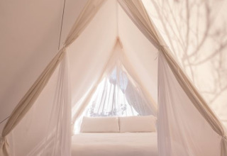 Vista interna di una tenda safari Cabin con letto bianco al Wecamp Cala Montgó in Spagna.