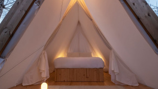 Innenansicht des Cabin Tent Safari-Zeltes mit gemütlichem Bett, Holzdetails und sanfter Beleuchtung.