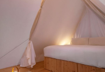 Intérieur de la Cabin Tent au Wecamp Cala Montgó en Espagne avec sol en bois, grand lit et lumière douce.