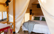 Binnenzicht van een safaritent met tweepersoonsbed en deken bij Glamping Couple, Wecamp Cabo de Gata, Spanje.