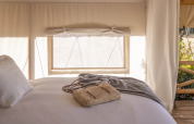 Indvendigt billede af et glamping telt ved Wecamp Cabo de Gata, Spanien, med en seng og stråtaske.