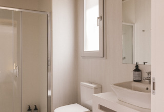 Modern, compact badkamer in een tiny house bij Wecamp Cala Montgó, Spanje, met houten plafond en glazen douche.
