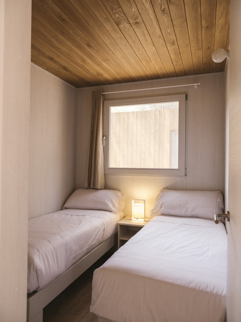 Kleine slaapkamer met twee eenpersoonsbedden in Mobil Home Family Wood bij Wecamp Cala Montgó, Spanje.