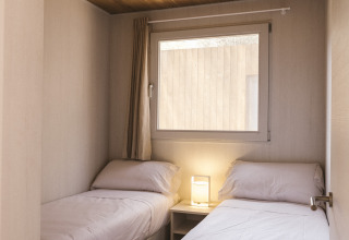 Kleine slaapkamer met twee eenpersoonsbedden in Mobil Home Family Wood bij Wecamp Cala Montgó, Spanje.