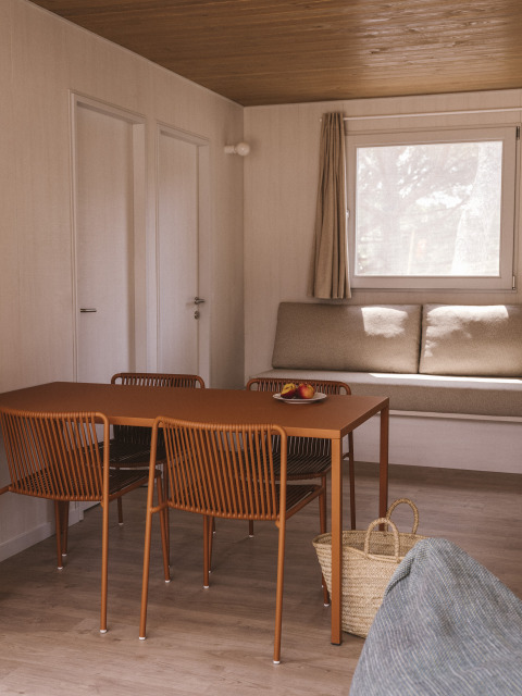 Modern interieur van MOBIL HOME FAMILY WOOD bij Wecamp Cala Montgó, Spanje, met eettafel en zitbank.