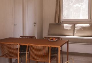 Modern interieur van MOBIL HOME FAMILY WOOD bij Wecamp Cala Montgó, Spanje, met eettafel en zitbank.
