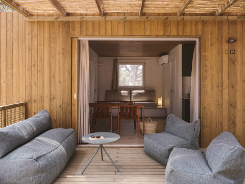 Buitenlounge met zachte stoelen op de veranda van tiny house MOBIL HOME FAMILY WOOD, binnen te zien.