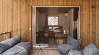 Buitenlounge met zachte stoelen op de veranda van tiny house MOBIL HOME FAMILY WOOD, binnen te zien.