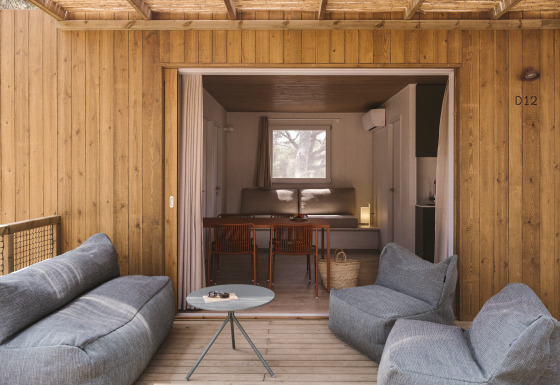 Buitenlounge met zachte stoelen op de veranda van tiny house MOBIL HOME FAMILY WOOD, binnen te zien.