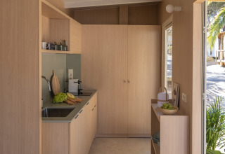 Kompakte, moderne Küchenzeile im MOBILE HOME FAMILY bei Wecamp Cala Montgó, Spanien, mit Holzverkleidung.