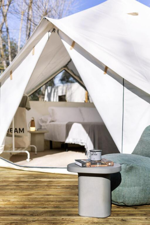 View of a spacious Bell Tent Plus at Wecamp San Sebastián, Spain, featuring a wooden deck and cozy interior setup.