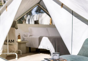 Ein Blick in ein geräumiges Bell Tent Plus im Wecamp San Sebastián, Spanien, mit Holzterrasse und gemütlicher Einrichtung.