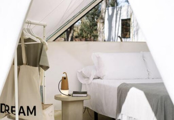 Intérieur d'une tente safari luxueuse avec un lit confortable, portant, table et lumière naturelle douce.