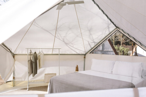 Intérieur de la tente safari Bell Tent au Wecamp San Sebastián en Espagne avec lit et portant à vêtements.