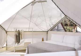 Intérieur de la tente safari Bell Tent au Wecamp San Sebastián en Espagne avec lit et portant à vêtements.