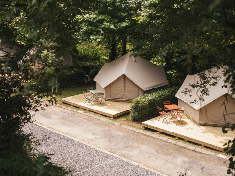 Tentes safari lumineuses sur terrasses en bois à Wecamp San Sebastián, Espagne, dans un cadre verdoyant.