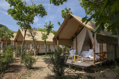 Safaritent Glamping Couple bij Wecamp San Sebastián in Spanje met een houten veranda en buitenstoelen.