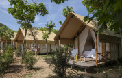 Tienda safari Glamping Couple en Wecamp San Sebastián, España, con terraza de madera y sillas exteriores.