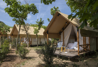 Tenda safari Glamping Couple presso Wecamp San Sebastián, Spagna, con veranda in legno e sedie all’aperto.