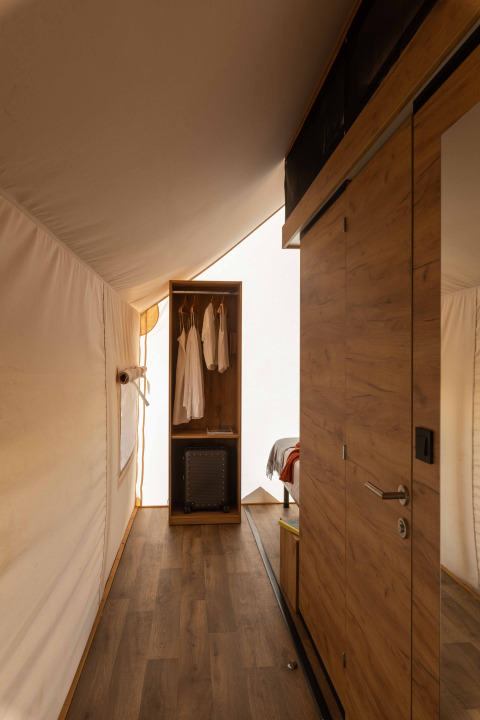 Vista interior de la tienda safari Glamping Family Plus en Wecamp San Sebastián, España, con detalles en madera.