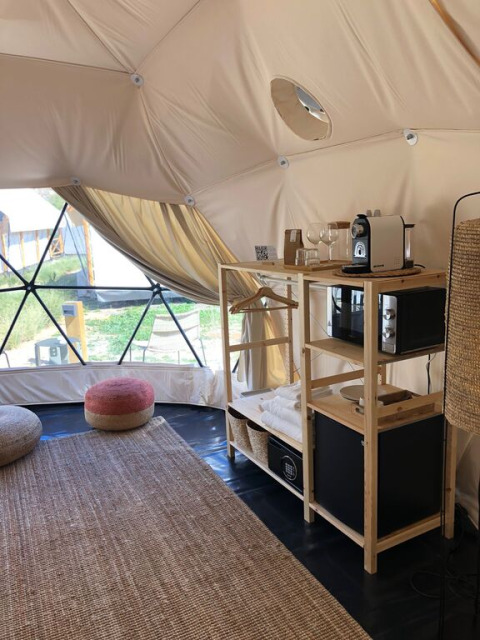 Interieur van een dome bij Wecamp Cabo de Gata, Spanje, met koffiezetapparaat, vloerkleed en zitkussens.
