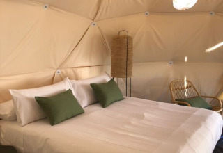 Slaapkamer met tweepersoonsbed, groene kussens en daglicht in een koepel bij Wecamp Cabo de Gata, Spanje.