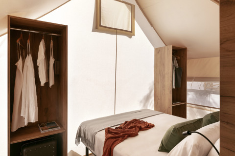 Innenraum eines Glamping-Komfortzelts bei Wecamp Cabo de Gata mit Bett und stilvollen Schränken.
