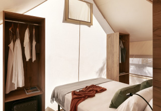 Innenraum eines Glamping-Komfortzelts bei Wecamp Cabo de Gata mit Bett und stilvollen Schränken.
