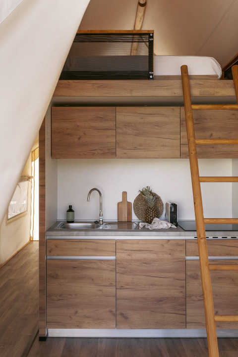 Pequeña cocina moderna y altillo en una tienda Glamping Comfort en Wecamp Cabo de Gata, España.