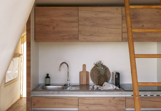 Pequeña cocina moderna y altillo en una tienda Glamping Comfort en Wecamp Cabo de Gata, España.