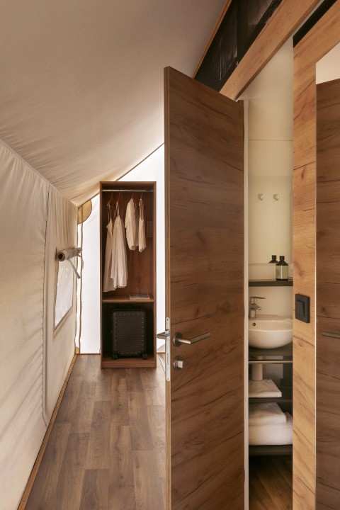 Vista interior de la tienda safari Glamping Comfort en Wecamp Cabo de Gata, España, con muebles de madera.
