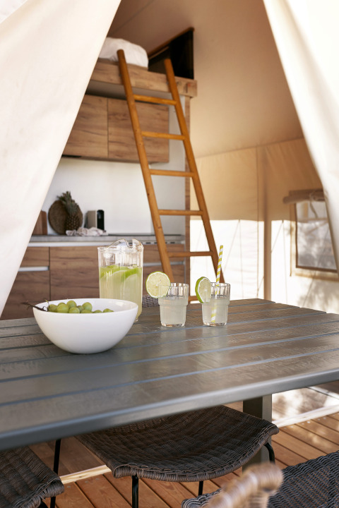Interior de una tienda safari en Glamping Comfort, Wecamp Cabo de Gata, España, con mesa y escalera al altillo.