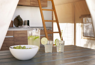 Interior de una tienda safari en Glamping Comfort, Wecamp Cabo de Gata, España, con mesa y escalera al altillo.